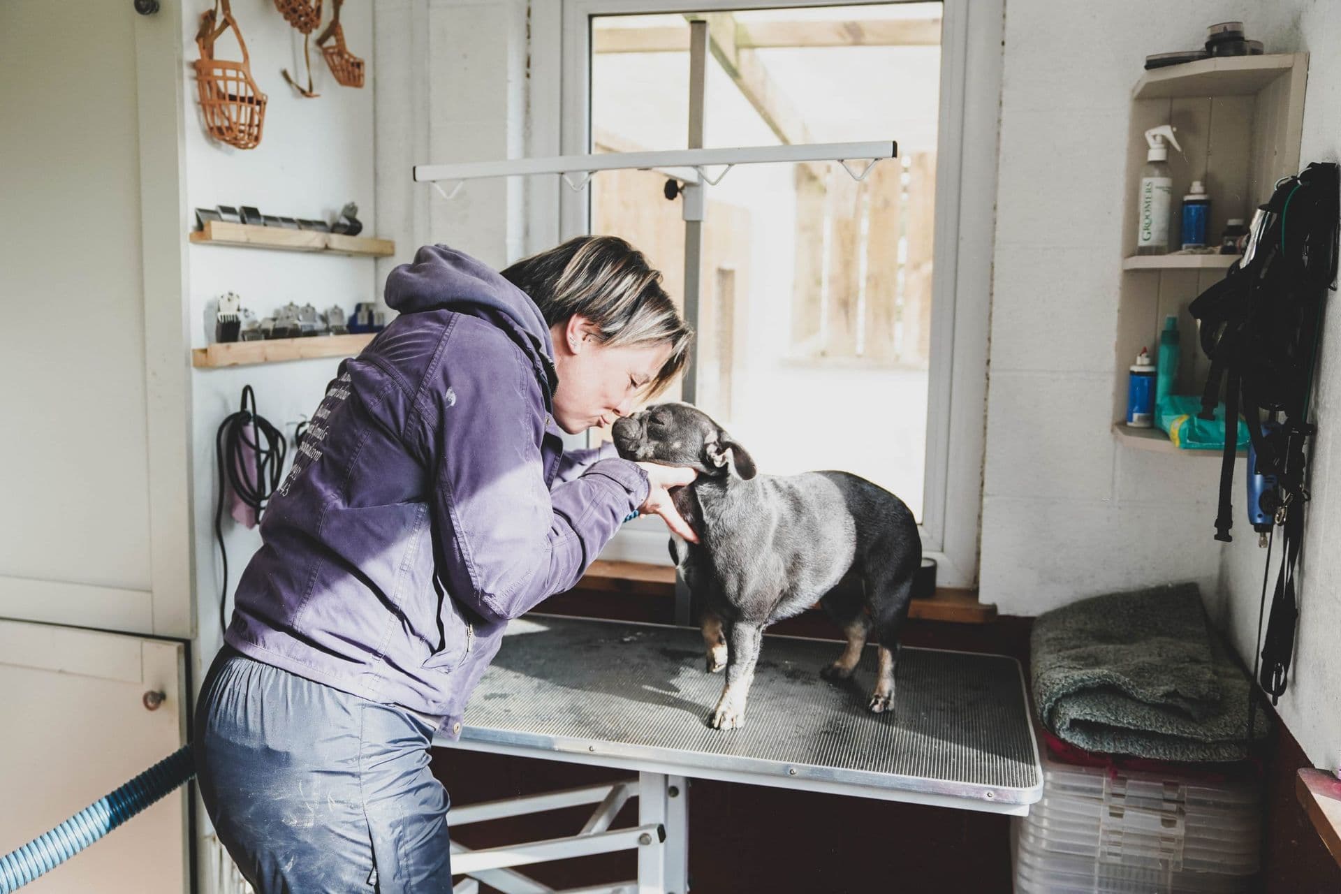 Emily from Blackdown Yard sharing a moment with a Staffie on the grooming table.